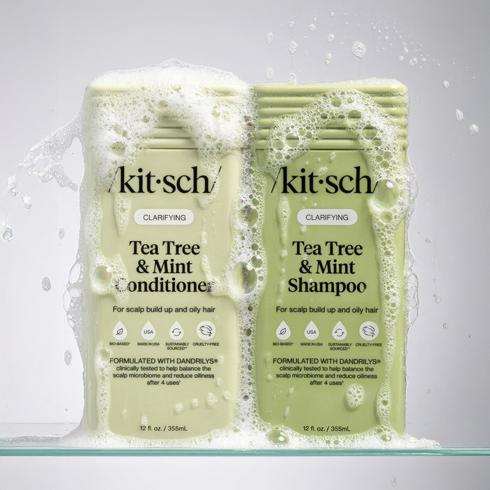Two bottles of 'kitsch' Tea Tree & Mint Shampoo and Conditioner on a gray background with water droplets.