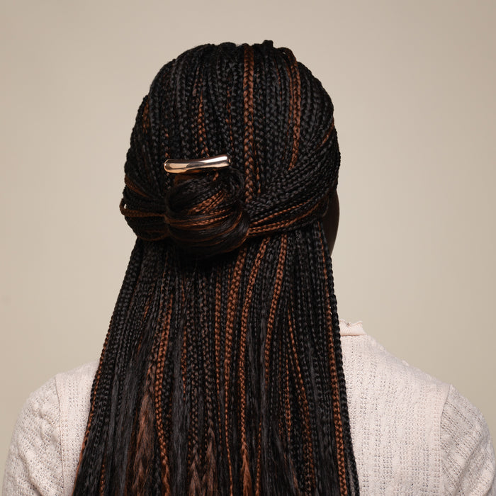 Person with braided hair styled in a bun against a neutral background