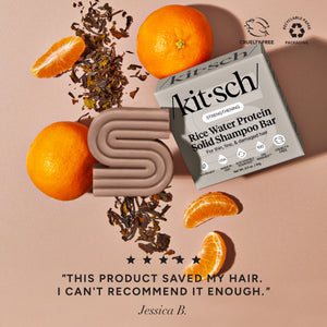 KITSCH Rice Water Shampoo Bar for Hair Growth — ingredient lifestyle flat lay on warm terracotta background — bar and retail box with mandarin oranges and dried tea leaves — Cruelty-Free | Recyclable Paper Packaging — 5-star customer review: "THIS PRODUCT SAVED MY HAIR. I CAN'T RECOMMEND IT ENOUGH." — Jessica B. — Formulated with Rice Tein NPNF® to increase hair volume by 20% after 5 washes